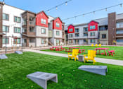 Thumbnail 55 of 76 - A grassy area with picnic tables and benches in front of apartment buildings.