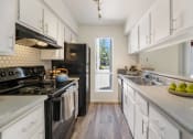 Thumbnail 21 of 36 - a kitchen with white cabinets and black appliances and a window  at Glen Brae, Glendale