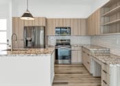 Thumbnail 52 of 81 - A modern kitchen with wooden cabinets and a marble countertop at Marketside Villas at Verrado, Buckeye, AZ