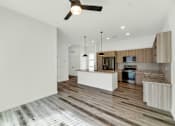 Thumbnail 53 of 81 - A modern kitchen with wooden floors and a ceiling fan at Marketside Villas at Verrado, Buckeye, AZ