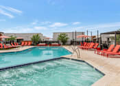 Thumbnail 70 of 81 - A large swimming pool with red lounge chairs around it at Marketside Villas at Verrado, Buckeye, AZ
