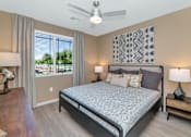 Thumbnail 20 of 54 - A bedroom with a large bed, a ceiling fan, and a view of the outdoors through the window.