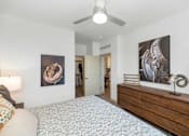 Thumbnail 21 of 54 - A bedroom with a bed, a ceiling fan, and two paintings on the wall.