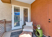 Thumbnail 29 of 54 - A balcony with a white chair, a green stool, and a white pillow.