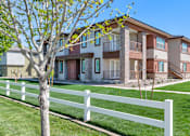 Thumbnail 48 of 54 - A white picket fence in front of a row of apartment buildings.