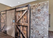 Thumbnail 51 of 54 - A large wooden door with a decorative tile wall on the side.