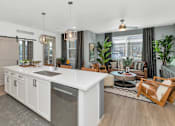 Thumbnail 8 of 54 - A modern kitchen with a large island and a dining area with a table and chairs.