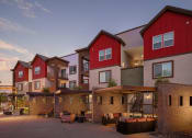 Thumbnail 28 of 76 - a group of townhomes with red and white facades at dusk at Weylyn Luxury Apartments, Laveen, AZ, 85339