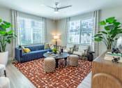 Thumbnail 18 of 52 - A living room with a blue couch, a red patterned rug, and a ceiling fan.