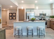 Thumbnail 15 of 52 - A kitchen with a white island and three bar stools.