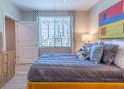 Thumbnail 23 of 52 - A bedroom with a bed, a dresser, and a painting on the wall.
