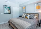 Thumbnail 9 of 52 - A bedroom with a bed, nightstand, and two framed pictures on the wall.