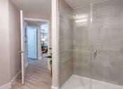 Thumbnail 14 of 52 - A bathroom with a walk-in shower and a doorway leading to another room.