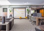 Thumbnail 43 of 52 - A modern office space with a large calendar on the wall and a variety of seating options.