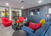 Thumbnail 36 of 52 - A living room with a blue couch, red chair, and a grey coffee table.
