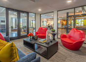 Thumbnail 37 of 52 - A modern living room with a grey sofa, red chairs and a coffee table.