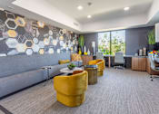 Thumbnail 46 of 52 - A modern office space with a grey sofa, yellow chairs, and a patterned wallpaper.