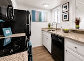 Thumbnail 13 of 20 - A kitchen with a black fridge and white cabinets.