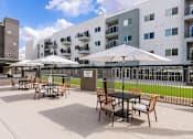 Thumbnail 4 of 26 - Outdoor patio with dining tables and umbrellas at Lucero Apartments, Phoenix, 85051