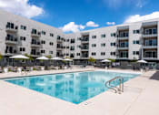 Thumbnail 2 of 26 - Swimming pool with lounge chairs and umbrellas at Lucero Apartments, Phoenix, Arizona