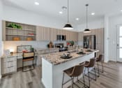 Thumbnail 11 of 35 - A modern kitchen with a marble countertop and wooden flooring.at Marketside Villas at Verrado, Buckeye, AZ