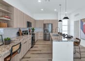 Thumbnail 12 of 35 - A modern kitchen with wooden floors and a marble countertop.at Marketside Villas at Verrado, Buckeye, 85396