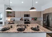 Thumbnail 13 of 35 - A kitchen with a granite countertop and stainless steel appliances.at Marketside Villas at Verrado, Buckeye, 85396