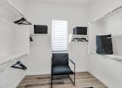 Thumbnail 21 of 35 - A black chair is in the middle of a white room with clothes hanging on a rail.at Marketside Villas at Verrado, Arizona, 85396
