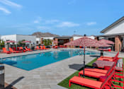 Thumbnail 3 of 35 - A pool surrounded by red chairs and umbrellas.at Marketside Villas at Verrado, Buckeye, 85396