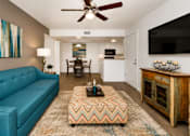Thumbnail 12 of 20 - A living room with a blue couch and a chevron patterned ottoman.