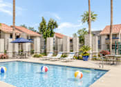 Thumbnail 8 of 20 - A pool with a blue umbrella and four beach balls.