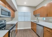 Thumbnail 19 of 37 - a modern kitchen with wood cabinets and stainless steel appliances