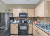Thumbnail 12 of 36 - A kitchen with a black stove top oven and a black microwave above the stove  at Montage at Pecos Ranch Apartments, Chandler, Arizona