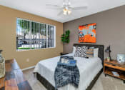 Thumbnail 16 of 36 - A bedroom with a large bed, a ceiling fan, and a window with blinds at Montage at Pecos Ranch Apartments, Arizona