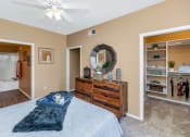 Thumbnail 17 of 36 - a bedroom with a bed and a dresser and a ceiling fan at Montage at Pecos Ranch Apartments, Chandler