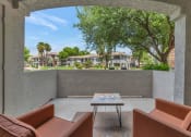 Thumbnail 21 of 36 - a patio with couches and a table in front of a tree at Montage at Pecos Ranch Apartments, Chandler