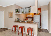 Thumbnail 23 of 36 - A kitchen with a white refrigerator, wooden countertop, and red stools at Montage at Pecos Ranch Apartments, Chandler, AZ, 85286