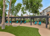 Thumbnail 28 of 36 - A patio with a black awning and blue chairs at Montage at Pecos Ranch Apartments, Chandler, AZ