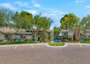 Thumbnail 36 of 36 - an empty parking lot in front of a building with trees at Montage at Pecos Ranch Apartments, Arizona