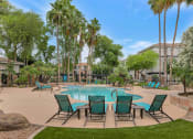 Thumbnail 3 of 36 - a swimming pool with patio furniture and palm trees at Montage at Pecos Ranch Apartments, Chandler, 85286
