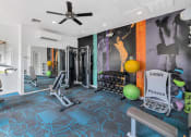 Thumbnail 6 of 36 - A gym with a variety of equipment including a bench, weights, and a squat rack at Montage at Pecos Ranch Apartments, Chandler