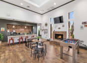 Thumbnail 7 of 36 - A room with a foosball table, bar stools, and a fireplace at Montage at Pecos Ranch Apartments, Chandler, AZ, 85286