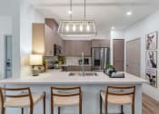 Thumbnail 29 of 76 - a kitchen with a large island with three chairsat Weylyn Luxury Apartments, Laveen, AZ 85339