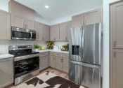 Thumbnail 31 of 76 - a kitchen with stainless steel appliances and white cabinets at Weylyn Luxury Apartments, Laveen, 85339