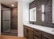 Thumbnail 14 of 51 - A bathroom with a brown tile shower and a white sink. at The Laurel Apartments, Arizona  