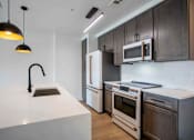 Thumbnail 13 of 51 - A modern kitchen with a white countertop and dark brown cabinets. at The Laurel Apartments, Arizona, 85286