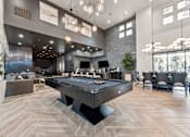 Thumbnail 19 of 51 - A pool table is in the middle of a room with a stone wall and a bar area. at The Laurel Apartments, Arizona  