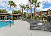 Thumbnail 40 of 51 - A pool area with a blue pool, lounge chairs, and palm trees. at The Laurel Apartments, Chandler, AZ  