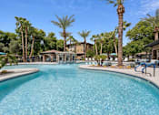 Thumbnail 33 of 51 - A large swimming pool surrounded by palm trees and lounge chairs. at The Laurel Apartments, Chandler  