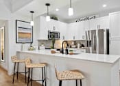 Thumbnail 3 of 51 - A kitchen with white cabinets and a white island with two barstools. at The Laurel Apartments, Arizona  